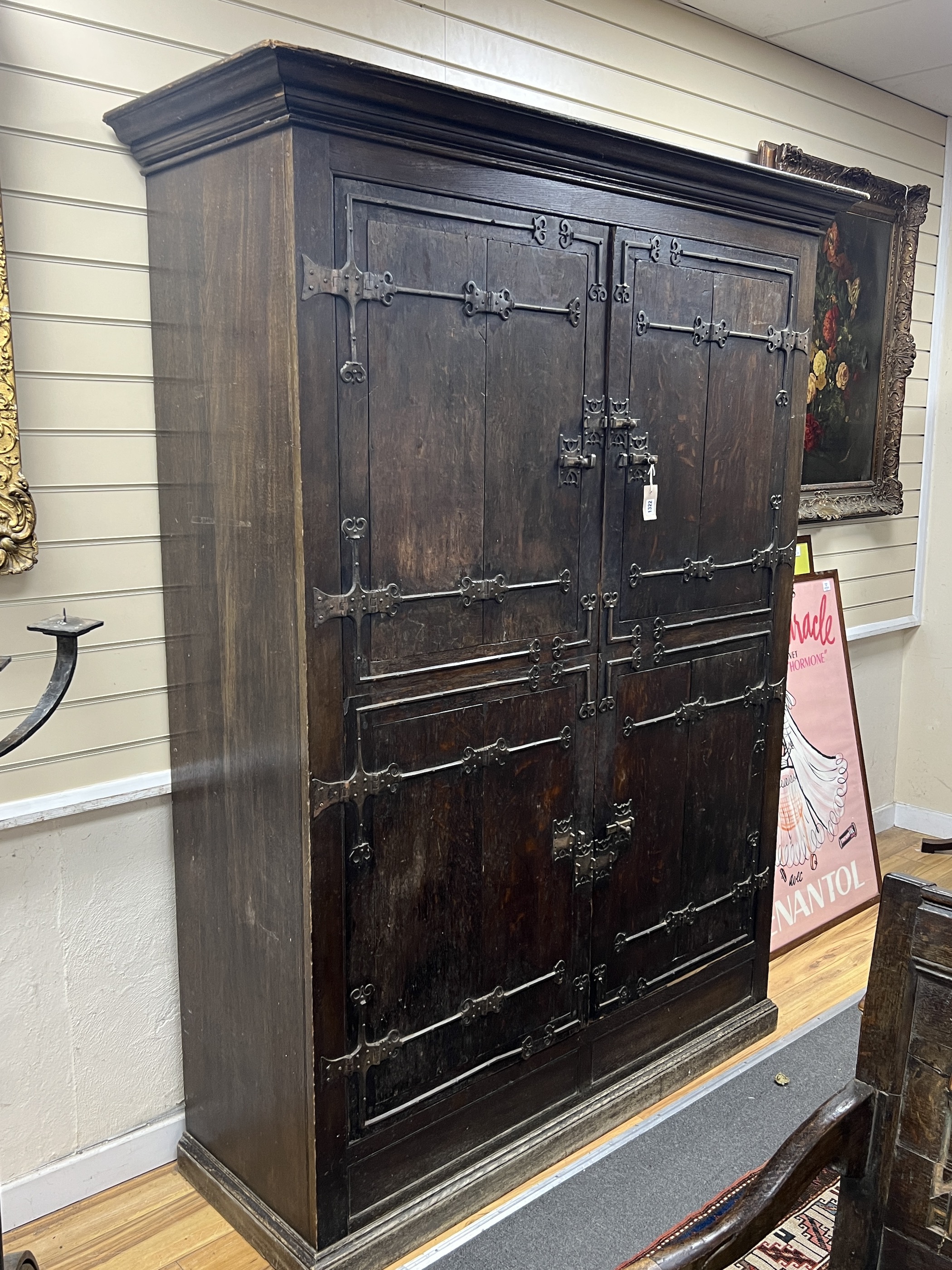 A pair of 16th century German or Netherlandish oak and wrought iron strapwork window shutters, later mounted on a cupboard, the moulded cornice above two pairs of hinged shutters, (previously bi-fold), mounted with elabo